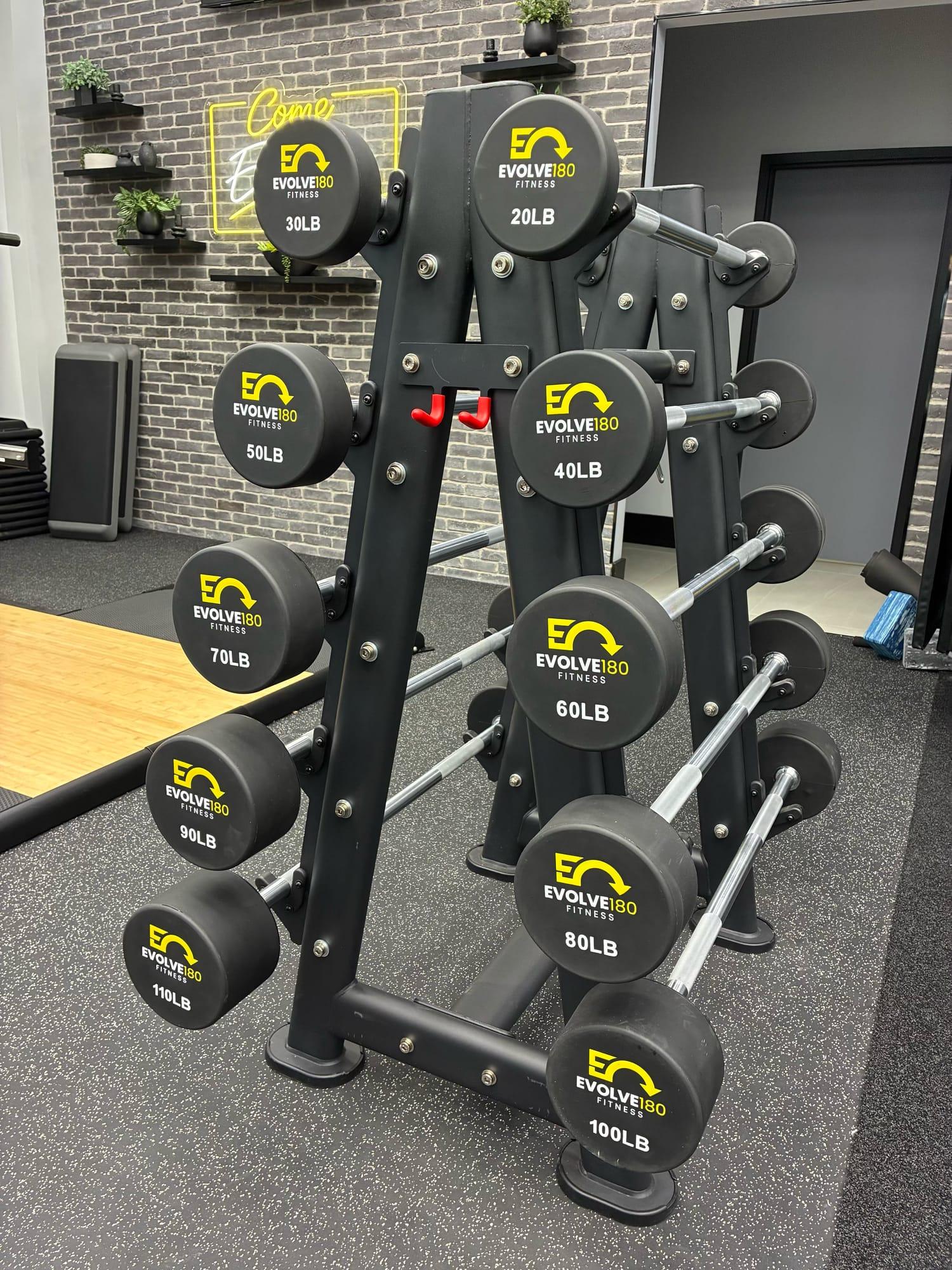 Rack of Evolve180 branded fixed-weight barbells