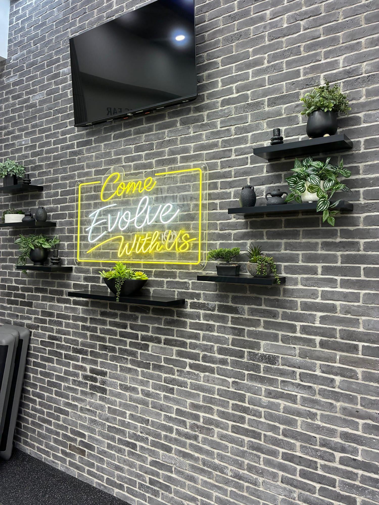 Brick feature wall with a Come Evolve With Us neon sign